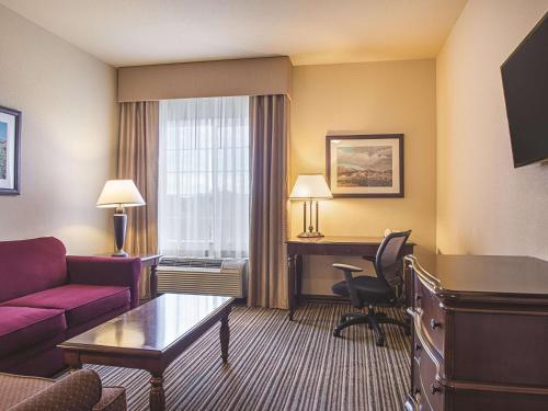 a living room with a couch and a desk in a hotel room at La Quinta by Wyndham Trinidad in Trinidad