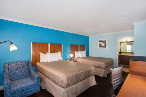 a hotel room with two beds and a chair at Days Inn by Wyndham Florida City in Florida City