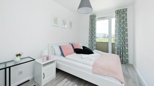 een witte slaapkamer met een bed en een raam bij Apartamenty Sun & Snow Konopnicka City in Krakau