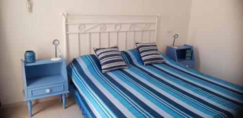 a bedroom with a bed with striped sheets and two pillows at Leuca Mon Amour in Leuca