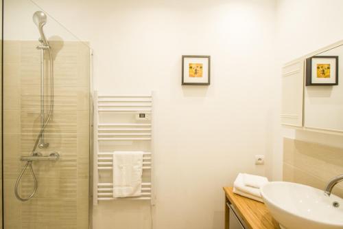 ein weißes Bad mit einer Dusche und einem Waschbecken in der Unterkunft Le Petit Carmes - Joli studio de caractère in Toulouse