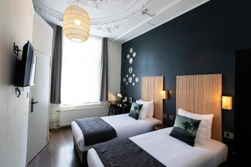 una camera d'albergo con due letti e una tv di Quentin Amsterdam Hotel ad Amsterdam