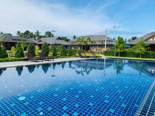 a large swimming pool with blue tiles in a yard at Benwadee Resort Pattaya in Ban Pong
