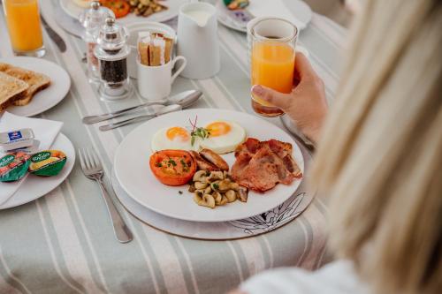 een vrouw aan een tafel met een bord ontbijtproducten bij Cornerstone Manor in Grahamstown