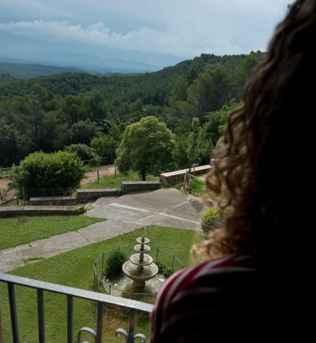 a woman looking out of a balcony at a garden at Hostal la Salut de Terrades in Terrades