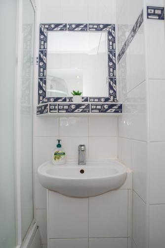 a white bathroom with a sink and a mirror at LOVELY ONE BEDROOM APARTMENT in Nové Zámky