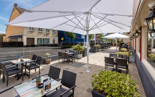a patio area with chairs, tables and umbrellas at Atlas Hotel in Valkenburg