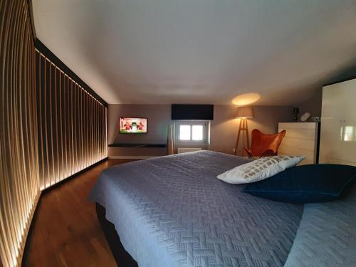 sypialnia z łóżkiem z niebieskim kocem i telewizorem w obiekcie MoAA - Modern Art Apartment w mieście Desenzano del Garda