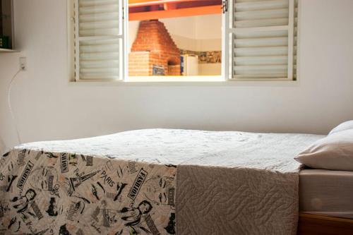uma cama num quarto com um espelho e uma janela em Casa temporada em São João Batista do Glória