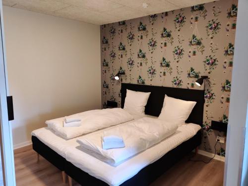 um quarto com uma cama com lençóis brancos e um papel de parede floral em List Inn em Brande
