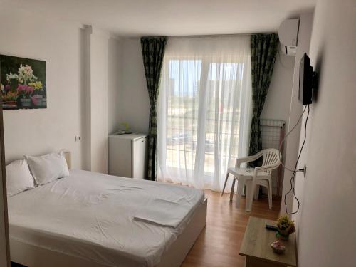 a bedroom with a bed and a window with a chair at Vila Bordei Verde in Mamaia Sat/Năvodari