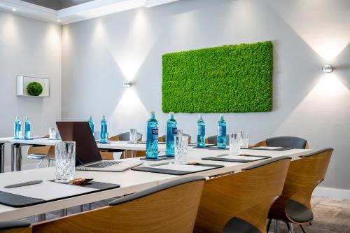 a conference room with a long table with chairs and blue bottles at Insel Hotel Bonn - Superior in Bonn