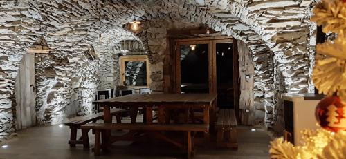 a room with a wooden table and a stone wall at Chalet Cormignano in Vezza dʼOglio