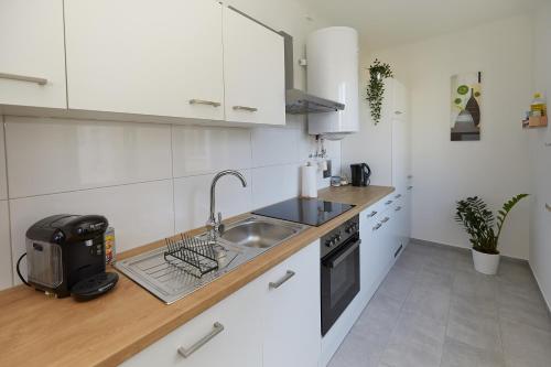 a kitchen with white cabinets and a sink and a stove at Gemütliche Wohnung in zentraler Lage in Graz