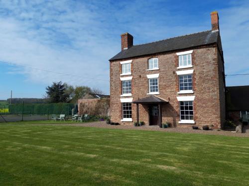 a large brick house with a large grass yard at Upper Eyton Farmhouse B&B in Shrewsbury