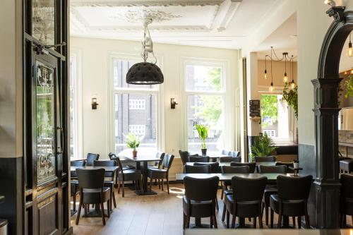 un comedor con mesas, sillas y ventanas en Quentin Amsterdam Hotel, en Ámsterdam