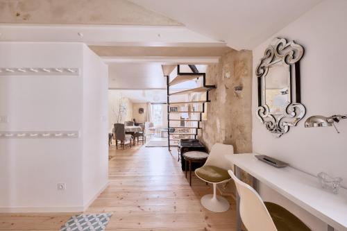 sala de estar con paredes blancas, mesa y sillas en Elégant appartement tout confort avec climatisation dans le centre historique de ST Emilion en Saint-Émilion