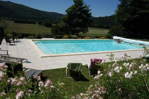 - une piscine dans une cour agrémentée de chaises et de fleurs dans l'établissement Chambres d'hôtes de charme Le Pradel, à Monceaux-sur-Dordogne