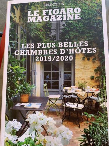 okładka czasopisma na patio ze stołami i krzesłami w obiekcie ORANGERIE de CHATEL-Selection FIGARO & ELLE Magazine w mieście Cleppé