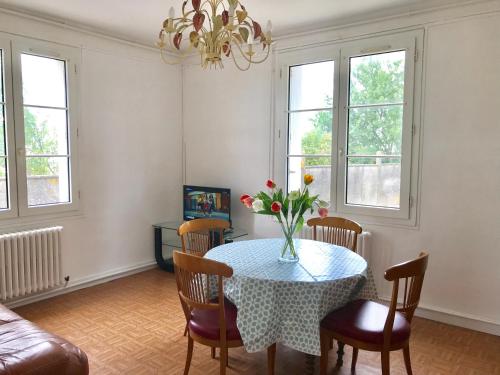 una sala de estar con una mesa con un jarrón de flores. en Hebergements le Camp d'Auneau - Leboudubout, en Auneau