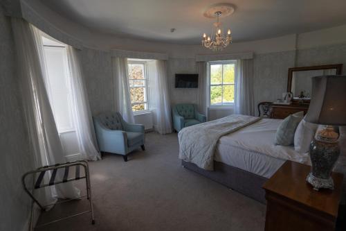 a bedroom with a bed and a chair and windows at Innishannon House Hotel in Inishannon