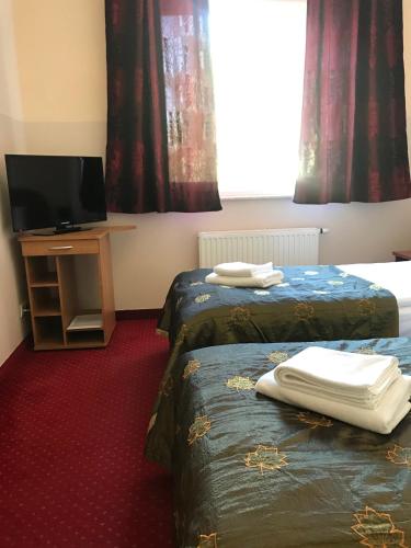 a hotel room with two beds and a flat screen tv at Motel Pintal in Gorzów Wielkopolski