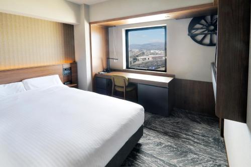 una camera d'albergo con letto, scrivania e finestra di JR Inn Hakodate a Hakodate