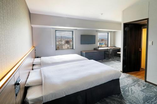 a bedroom with a large bed and a desk in it at JR Inn Hakodate in Hakodate