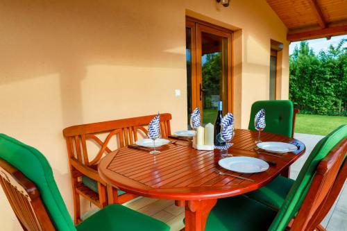 a wooden table with green chairs around it at Hullám Nyaraló in Balatonmáriafürdő