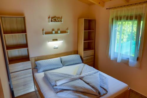 a bedroom with a bed with a window and shelves at Hullám Nyaraló in Balatonmáriafürdő