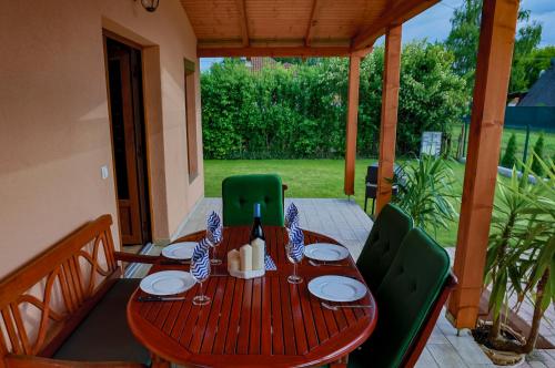 a wooden table with green chairs on a patio at Hullám Nyaraló in Balatonmáriafürdő