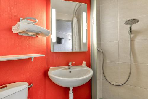 een rode badkamer met een wastafel en een douche bij B&B HOTEL Narbonne 2 in Narbonne