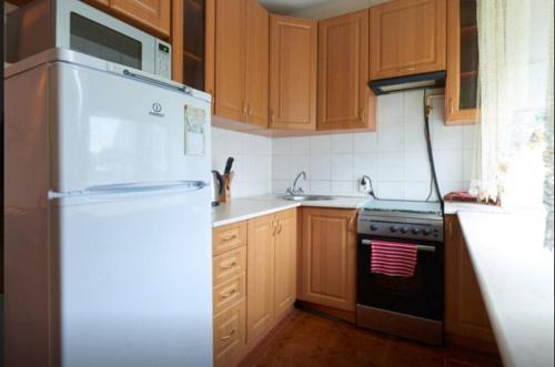 a kitchen with wooden cabinets and a white refrigerator at Двушка Печерск in Kyiv