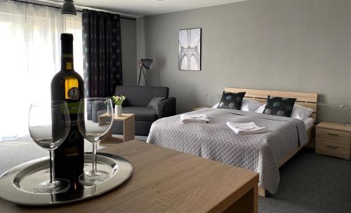 a bedroom with a bottle of wine and two glasses on a table at City Apartments in Liptovský Mikuláš