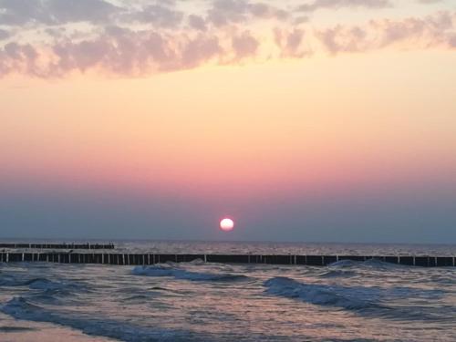 a sunset over the ocean with a pier at Platinium Rewal Aparthotel 17 in Rewal