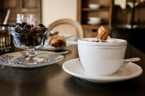 a cup of coffee sitting on a table with a dessert at Donna Carolina Luxury rooms in Cefalù
