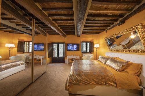 a bedroom with two beds and a mirror at La Togata Hotellerie de Charme Relais il Terrazzo in Montalcino