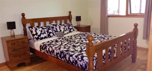 a bedroom with a wooden bed and two night stands at Treetops Hideaway Albury in Albury