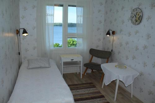 a bedroom with a bed and a table and a window at Labbnäs Semesterhem in Kimitoön