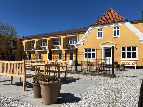 un bâtiment avec bancs et table devant lui dans l'établissement Kallehavegaard Badehotel, à Løkken