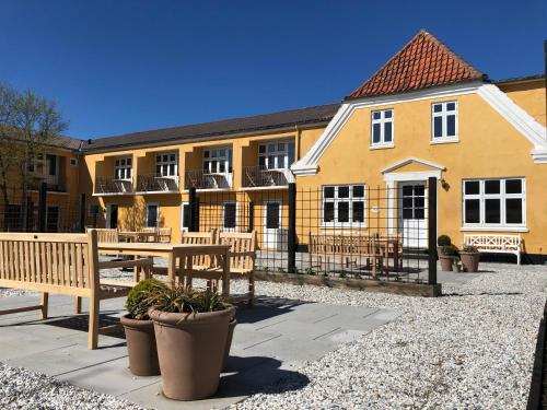 un edificio con bancos y una mesa frente a él en Kallehavegaard Badehotel, en Løkken