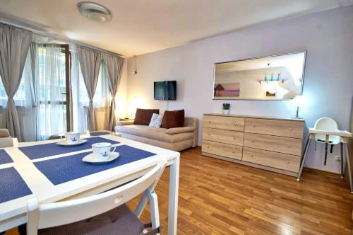 ein Wohnzimmer mit einem Tisch und ein Zimmer mit einem Sofa in der Unterkunft Apartament Park Zdrojowy 2 in Świnoujście