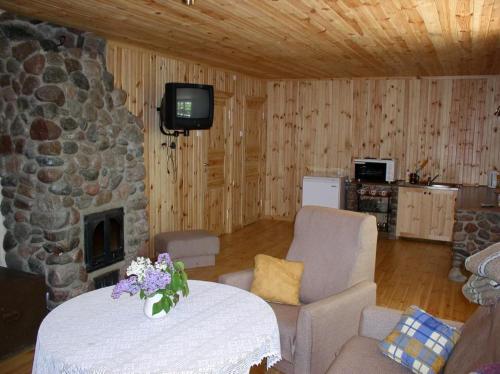 a living room with a stone fireplace and a tv at Marta-Lovise puhkemaja Aliine in Kipi
