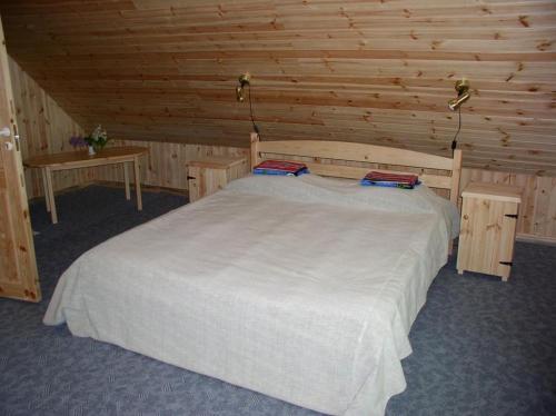ein Schlafzimmer mit einem weißen Bett in einem Holzzimmer in der Unterkunft Marta-Lovise puhkemaja Aliine in Kipi