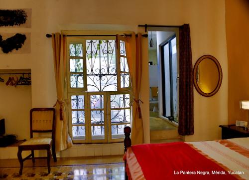 una camera da letto con finestra, letto e specchio di La Pantera Negra a Mérida