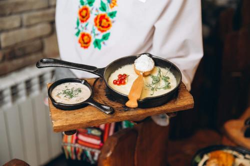a person holding a frying pan with food in it at Грибова хата in Bukovel