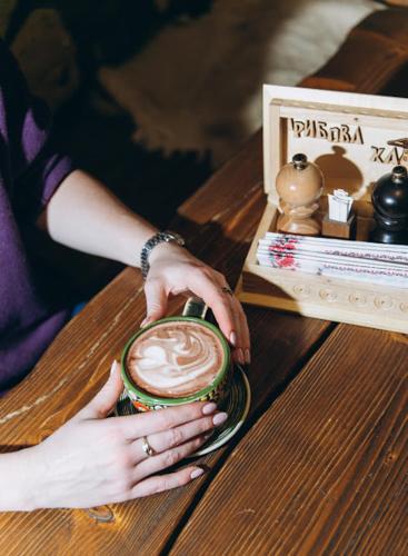 a woman is holding a cup with a drink at Грибова хата in Bukovel