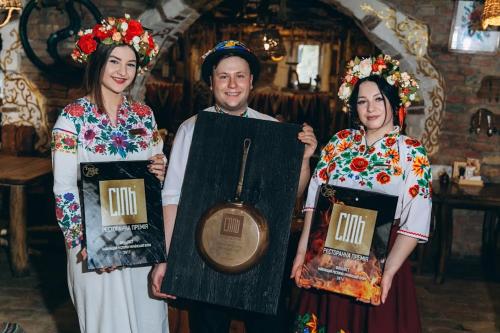 Un uomo e due donne in costume con una targa di Грибова хата a Bukovel