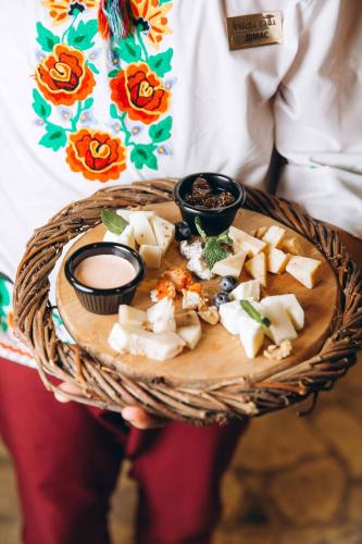 a person holding a plate of cheese and sauce at Грибова хата in Bukovel