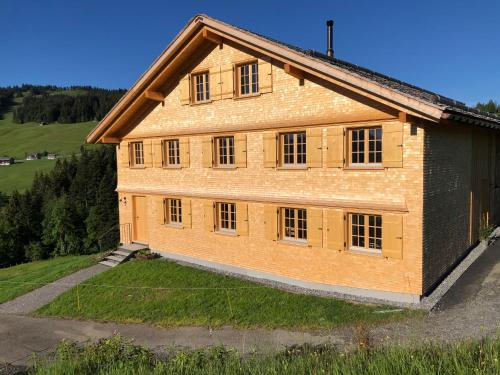 um grande edifício de tijolos com janelas numa colina em UNSER VORSÄSS - Geißkopf em Schwarzenberg im Bregenzerwald